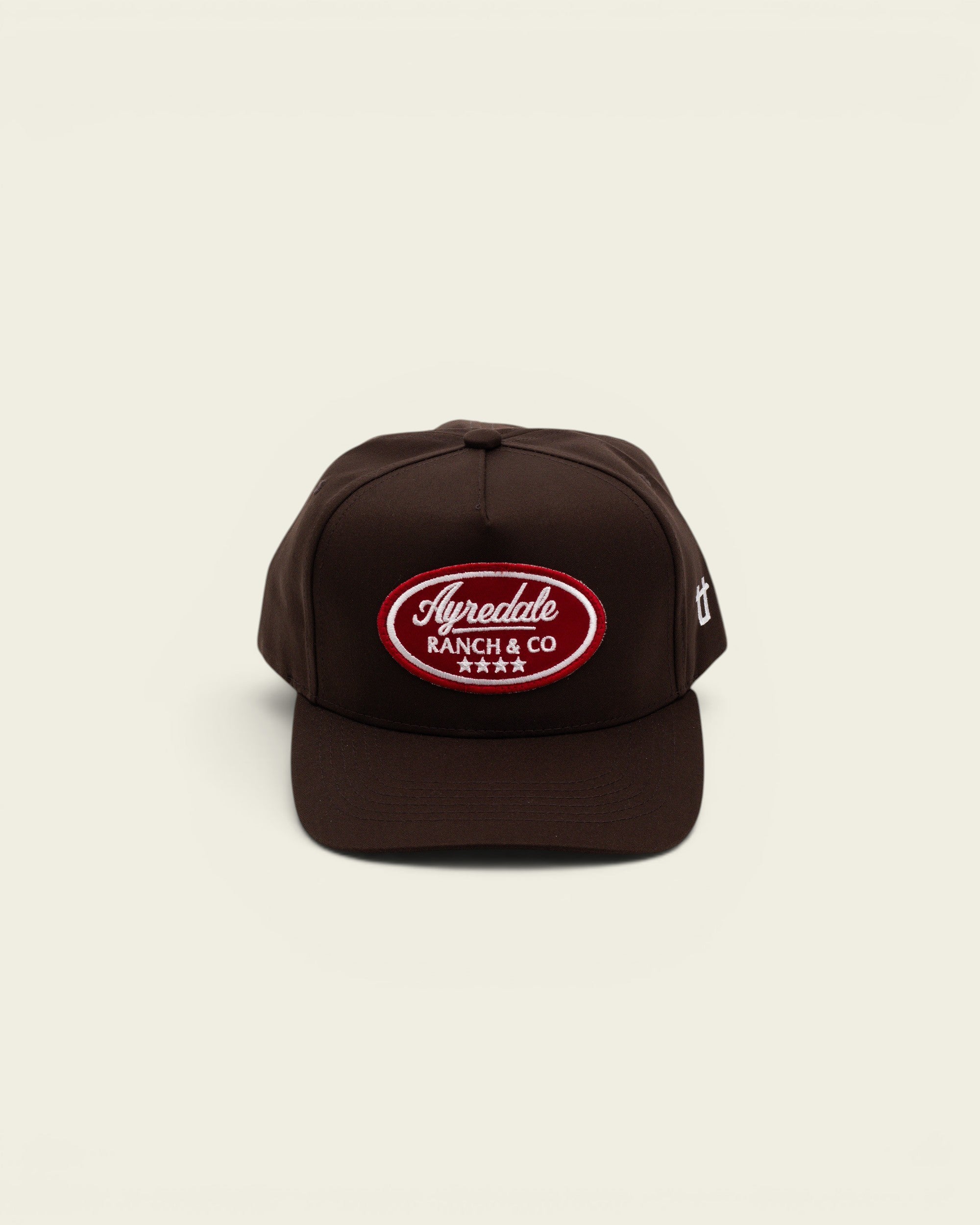 Ayredale Ranch & Co dark brown trucker hat with a red oval embroidered patch logo on the front