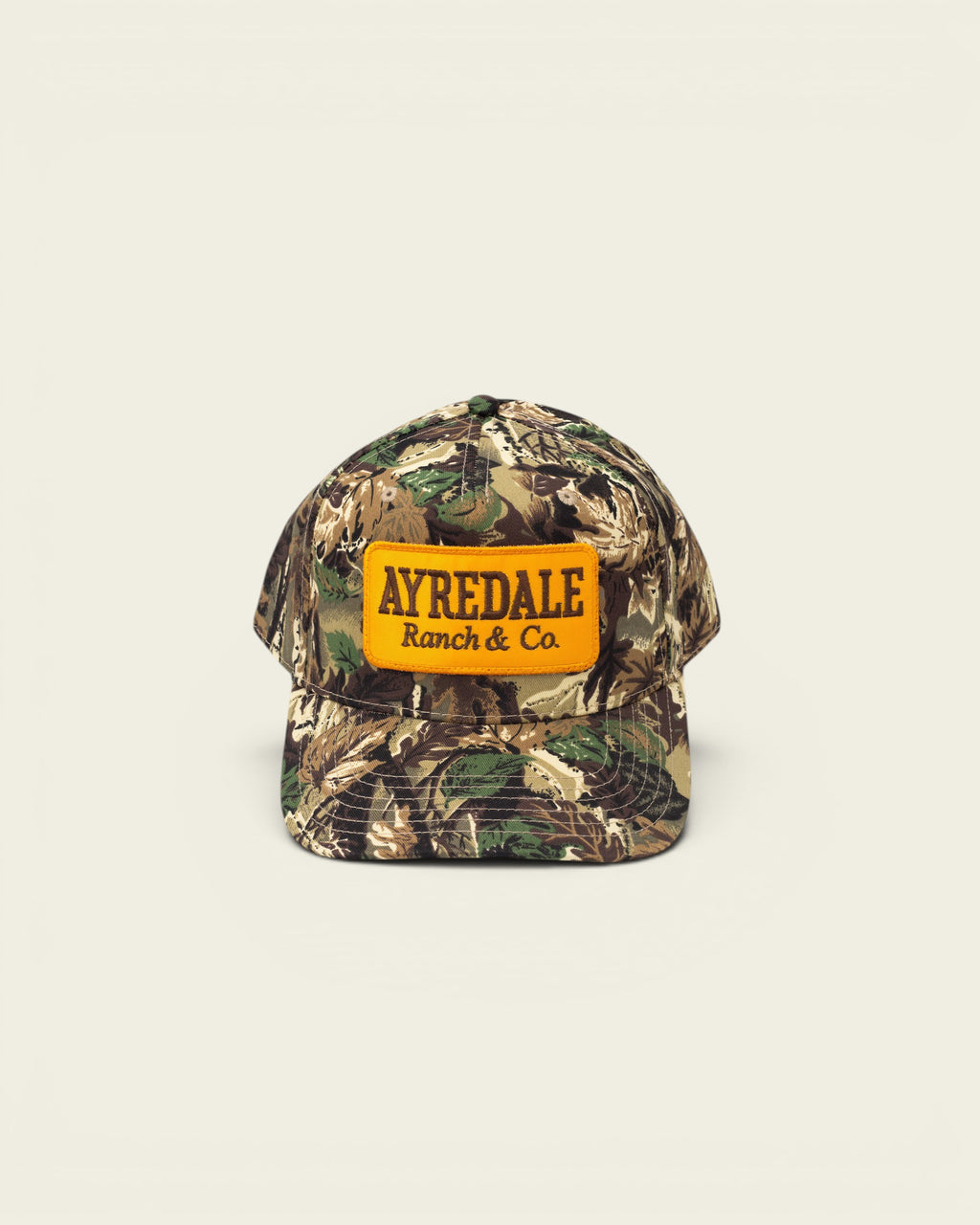 Ayredale Ranch & Co. camouflage baseball cap with orange patch. Adjustable strap back.