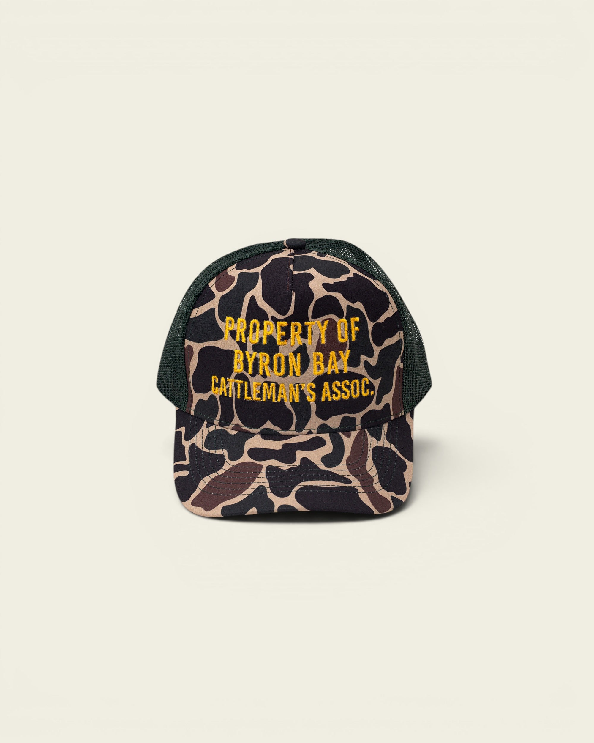 Ayredale Ranch & Co camouflage trucker hat with green mesh back and yellow embroidered text "PROPERTY OF BYRON BAY CATTLEMAN'S ASSOC."