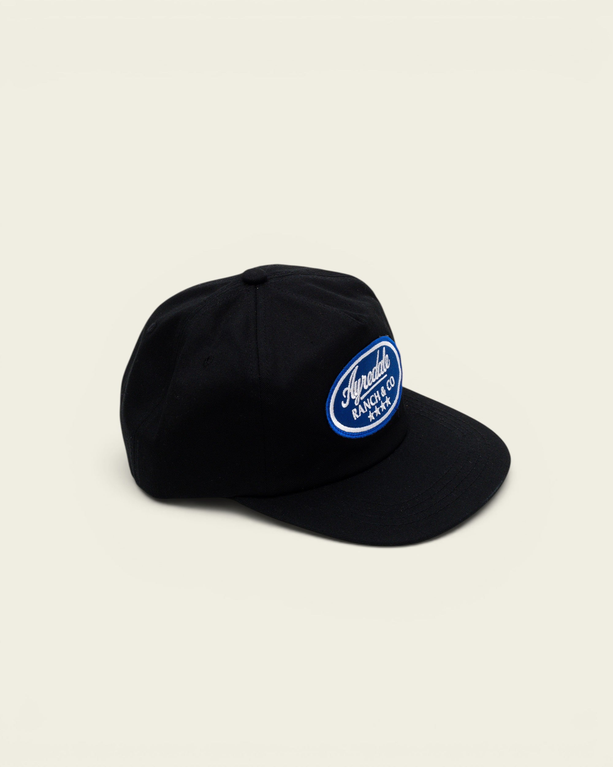 Ayredale Ranch & Co black baseball cap with a blue oval patch featuring white text and star embroidery.