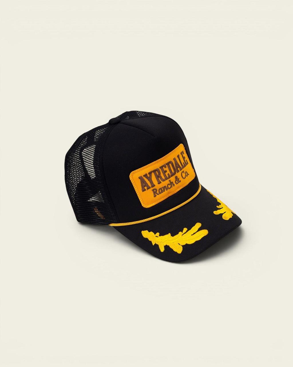 Ayredale Ranch & Co black trucker cap with yellow embroidered detail on the brim and logo patch.