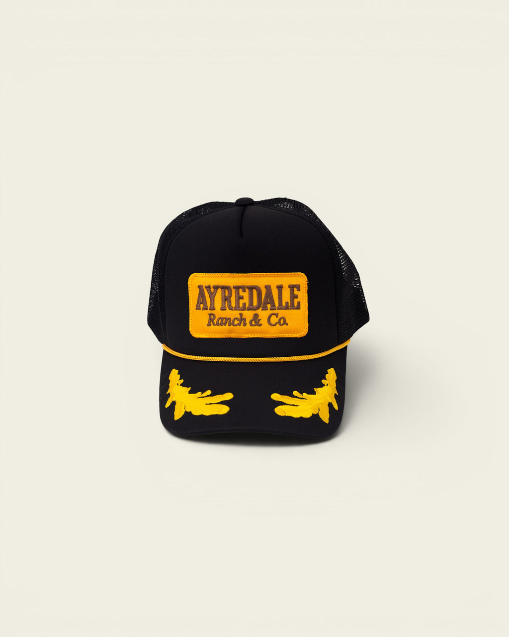 Ayredale Ranch & Co black trucker hat with yellow embroidered logo and flame details.