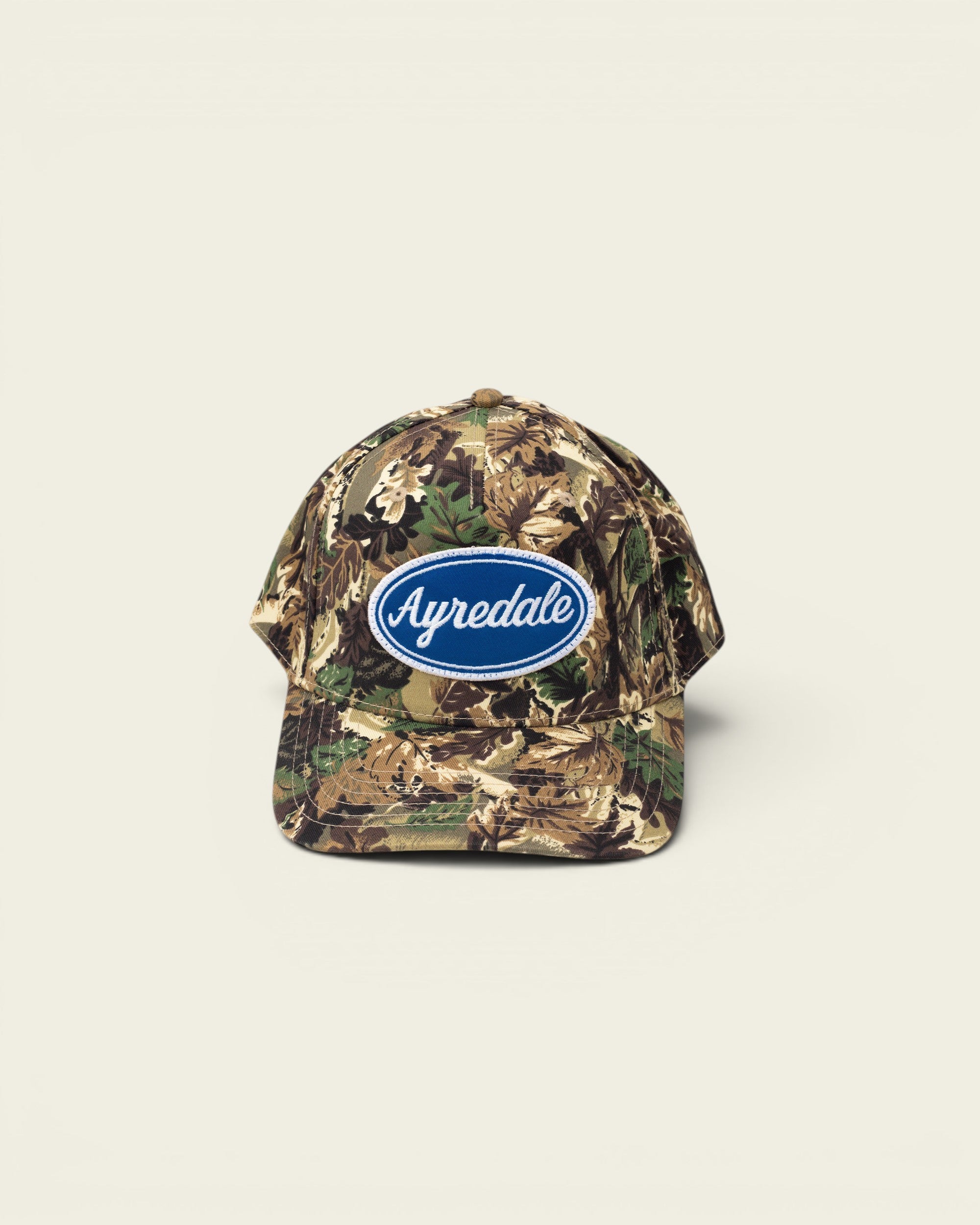 Ayredale Ranch & Co camouflage baseball cap with blue oval logo patch.