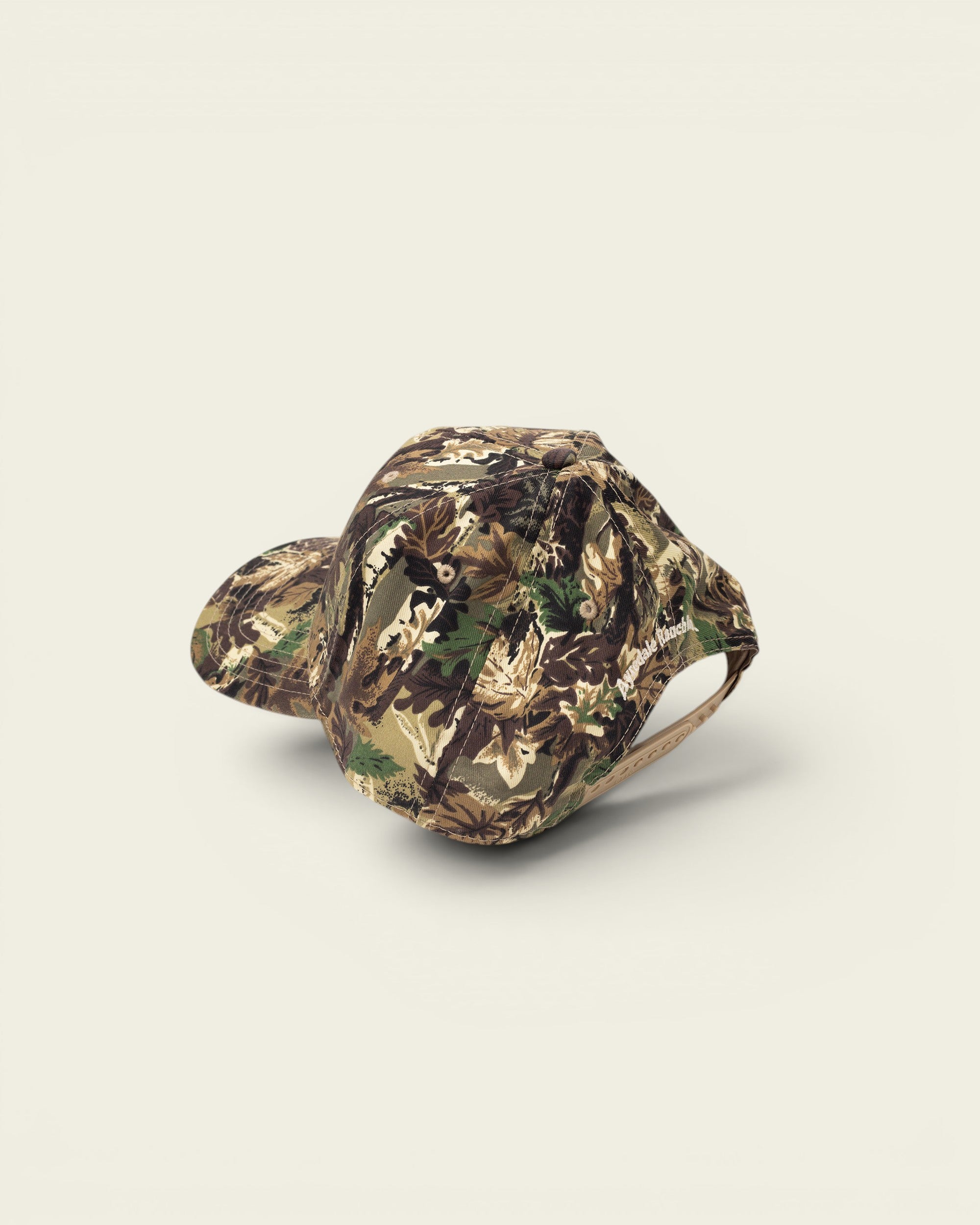 Ayredale Ranch & Co camouflage baseball cap with a flat brim and adjustable strap. Features a woodland leaf pattern.