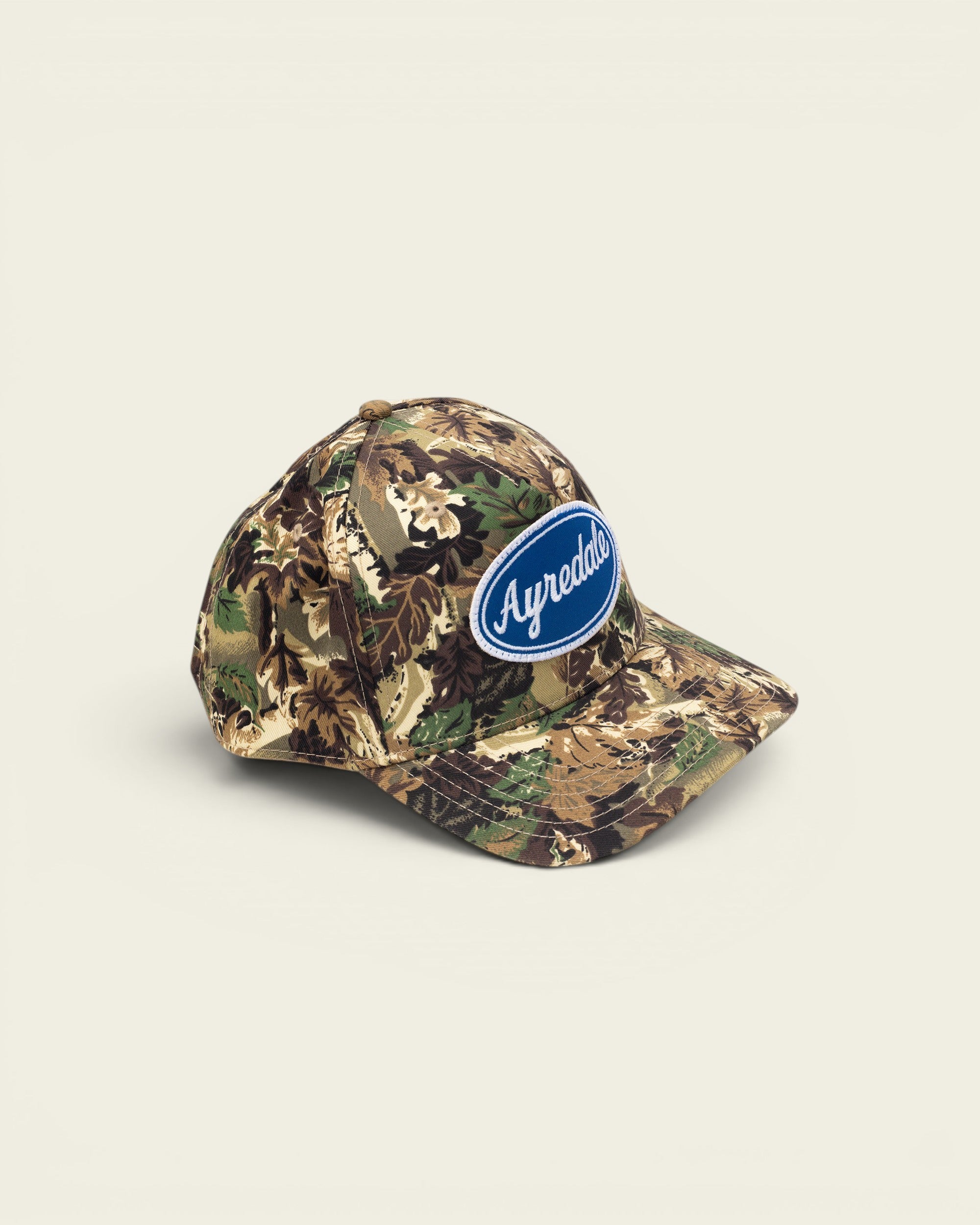 Ayredale Ranch & Co camouflage baseball cap with blue oval logo patch.