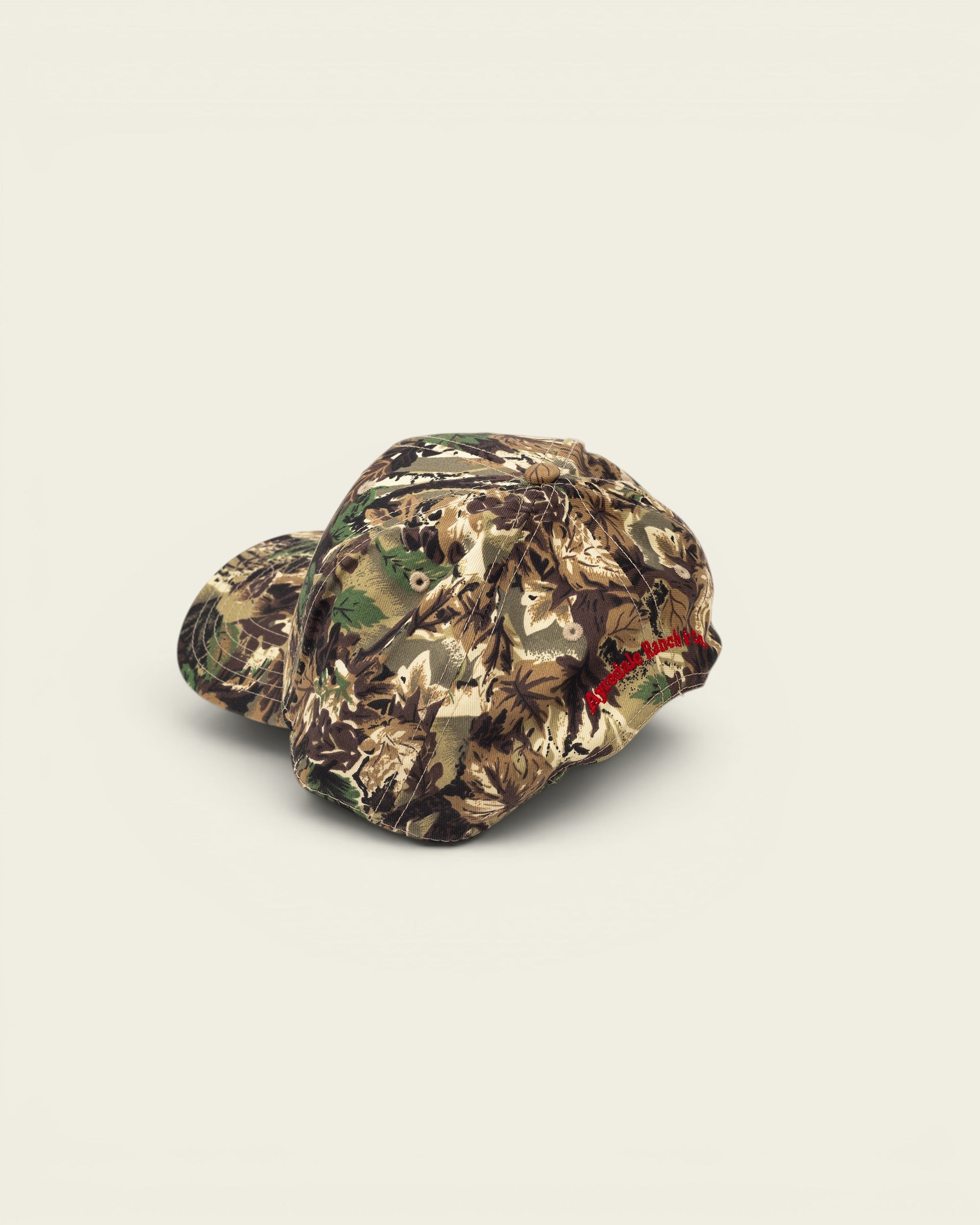 Ayredale Ranch & Co camouflage baseball cap with red embroidered logo on the side.