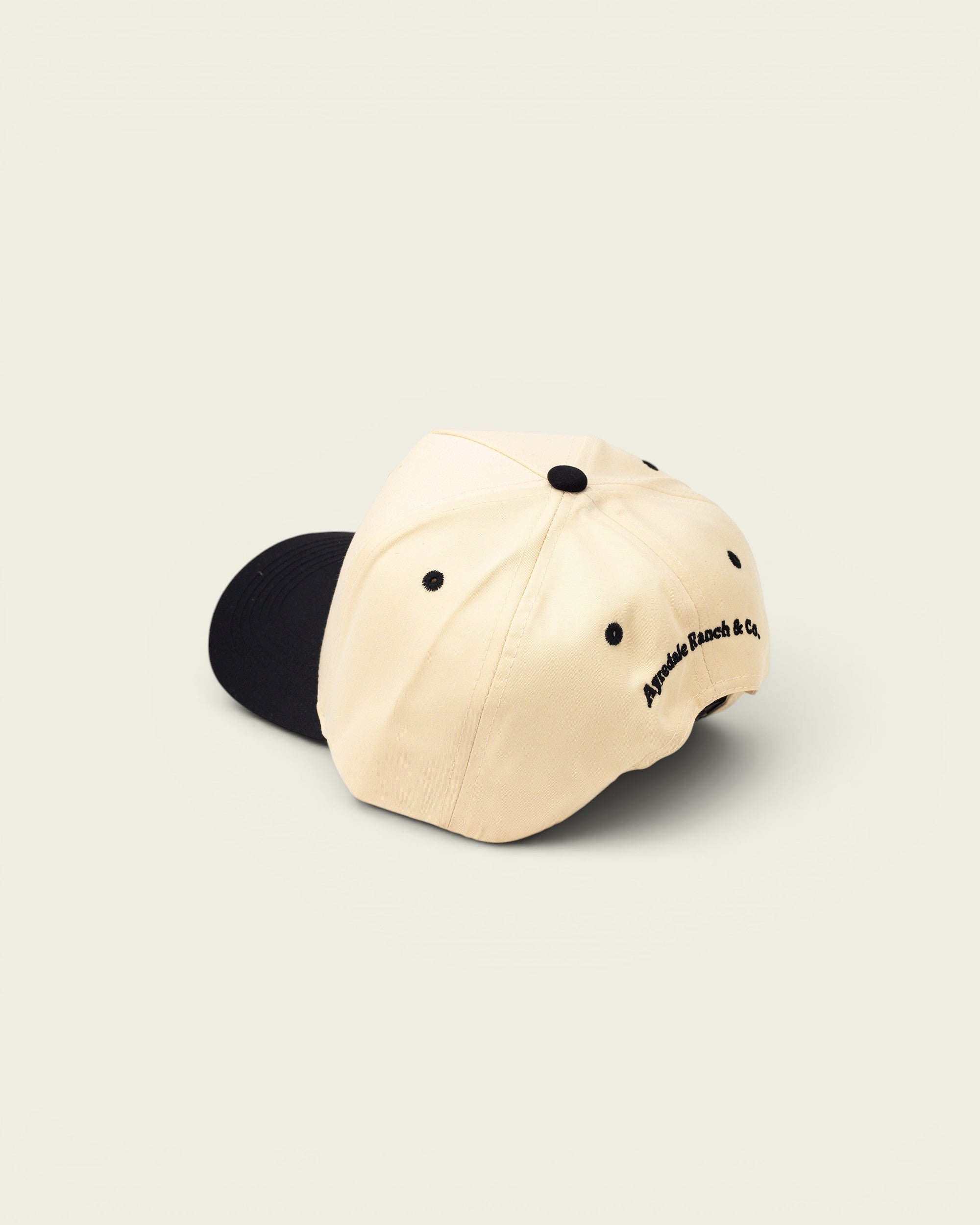 Ayredale Ranch & Co cream baseball cap with black accents and embroidered logo.