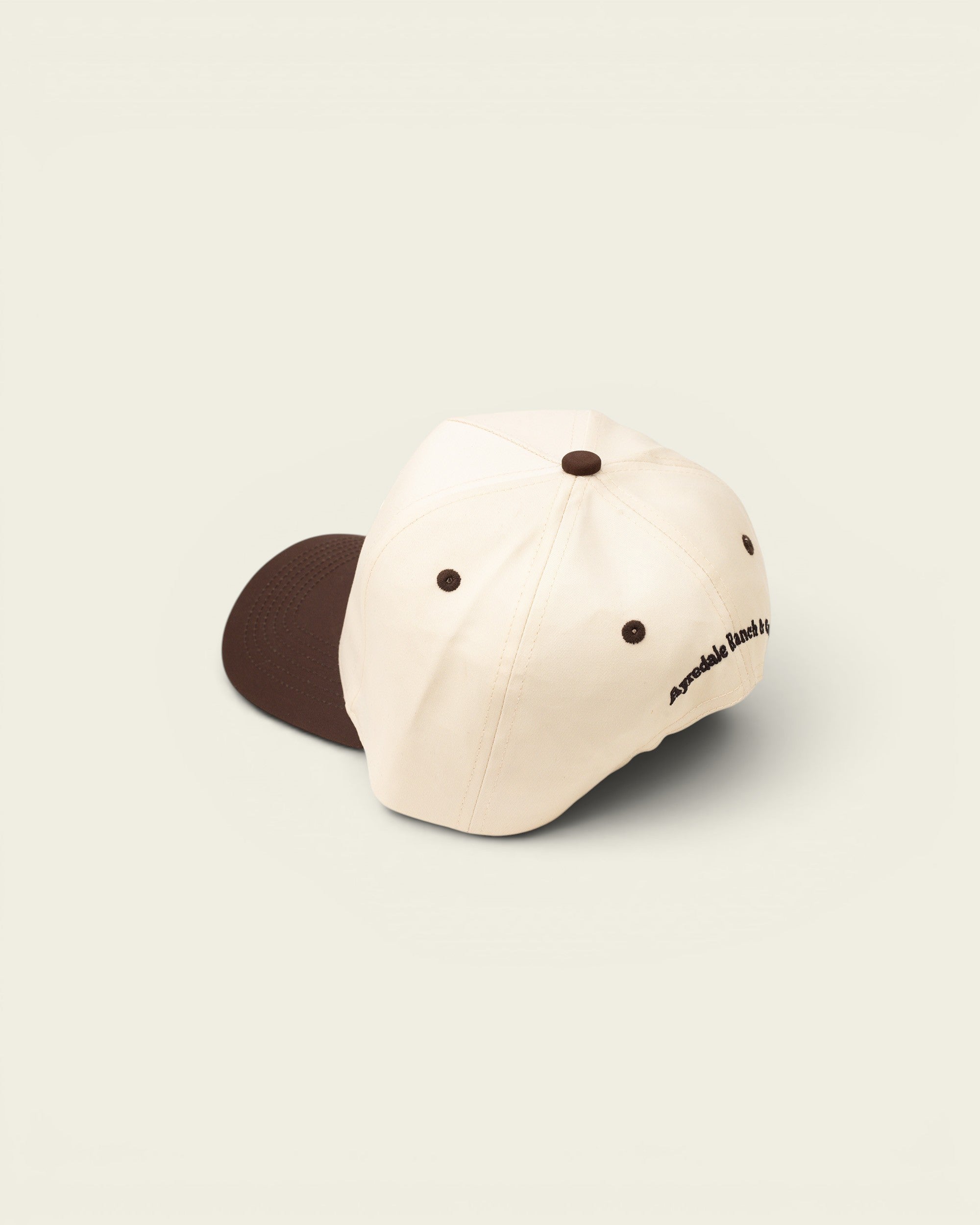 Ayredale Ranch & Co cream baseball cap with brown accents and embroidered logo on the side.