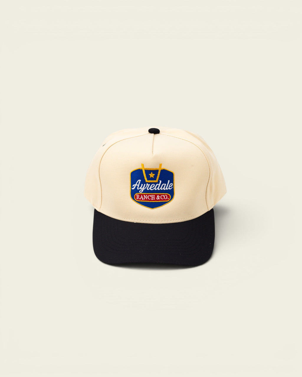 Ayredale Ranch & Co. cream baseball cap with black brim and embroidered logo.