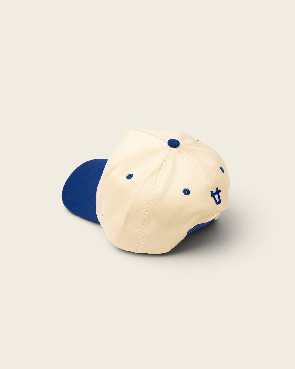 Ayredale Ranch & Co cream baseball cap with blue brim, button, eyelets, and embroidered logo.