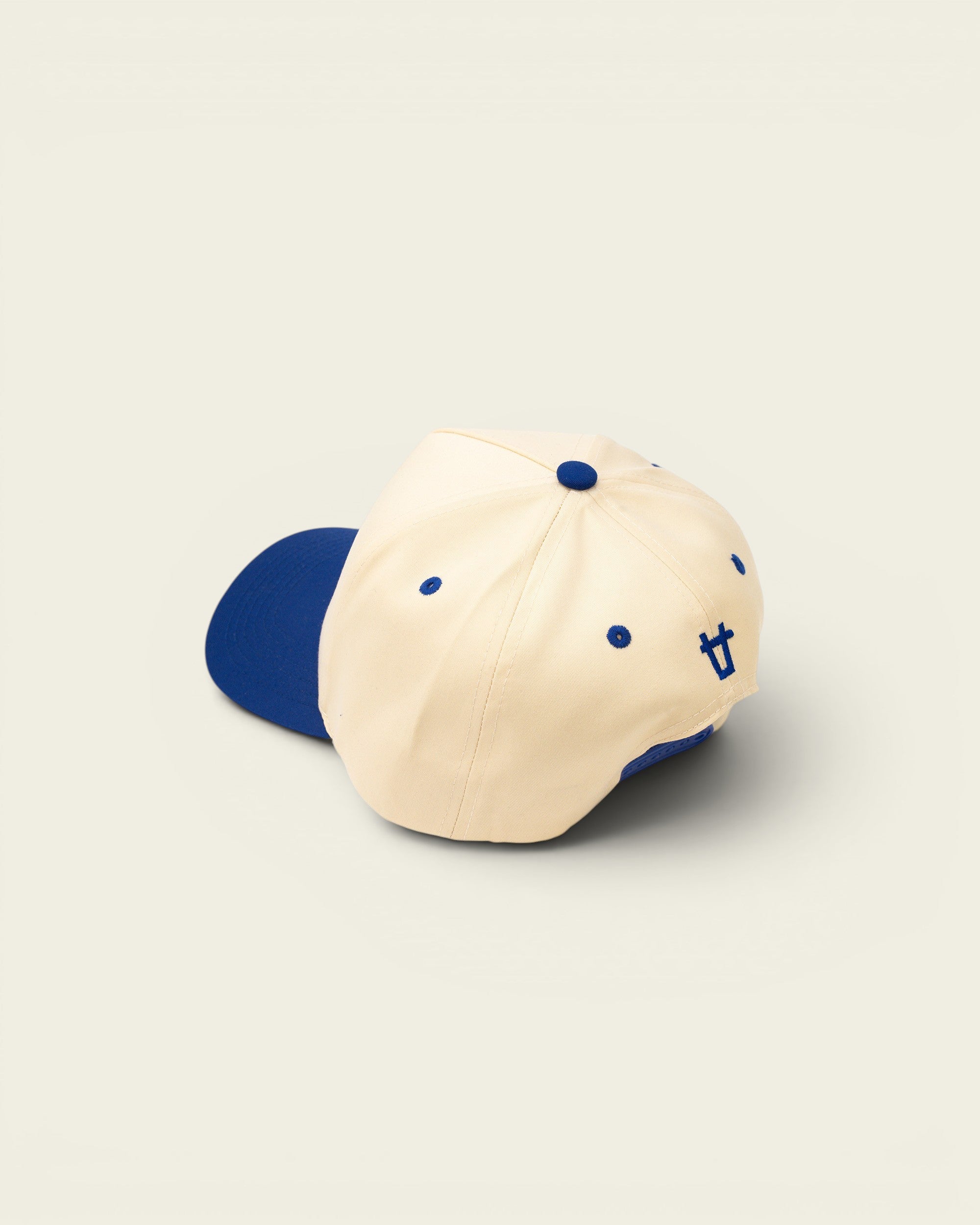 Ayredale Ranch & Co cream baseball cap with blue brim, button, eyelets, and embroidered logo.