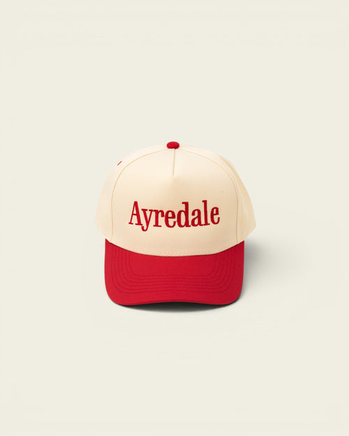 Ayredale Ranch & Co cream baseball cap with red brim and red embroidered text.