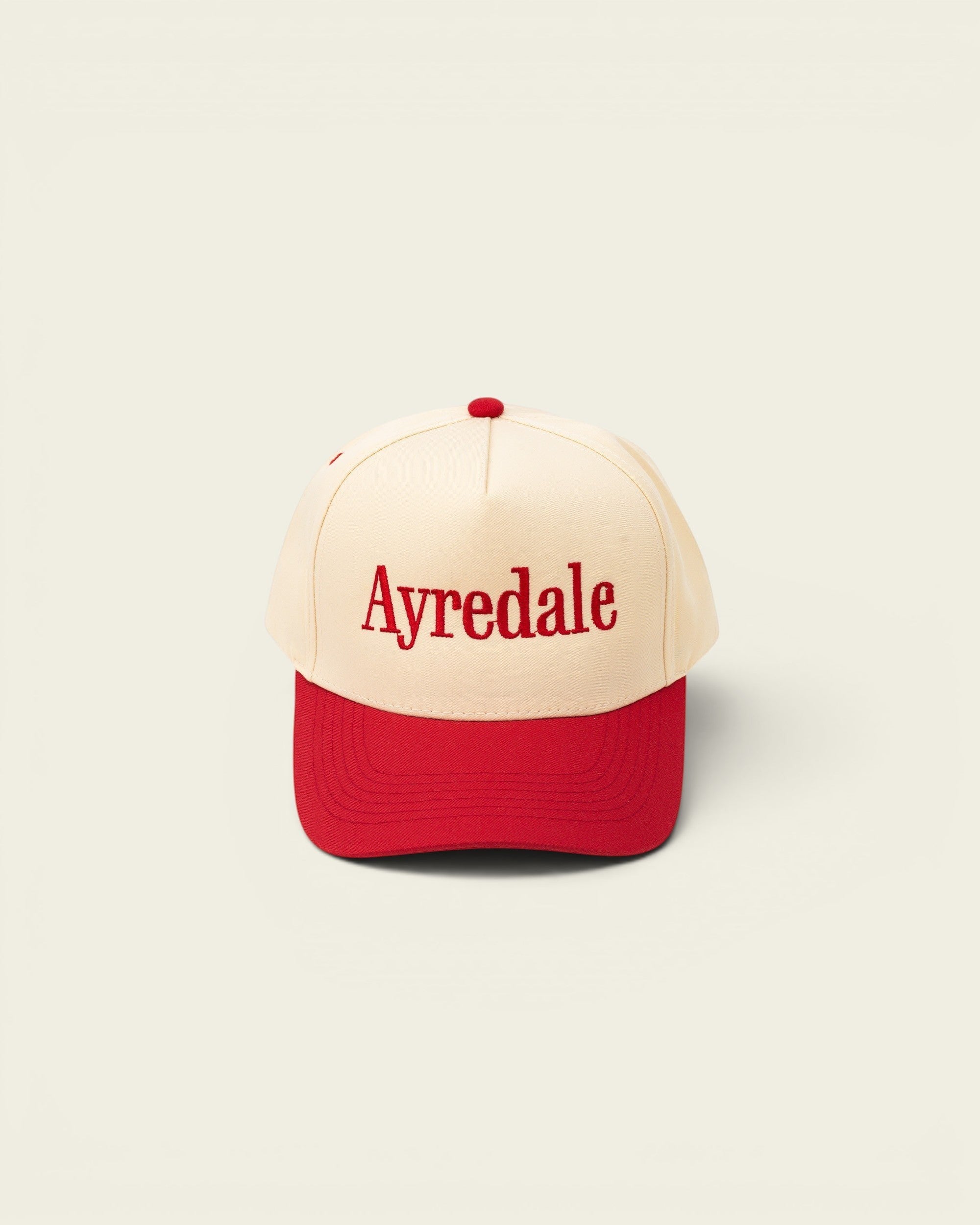 Ayredale Ranch & Co cream baseball cap with red brim and red embroidered text.