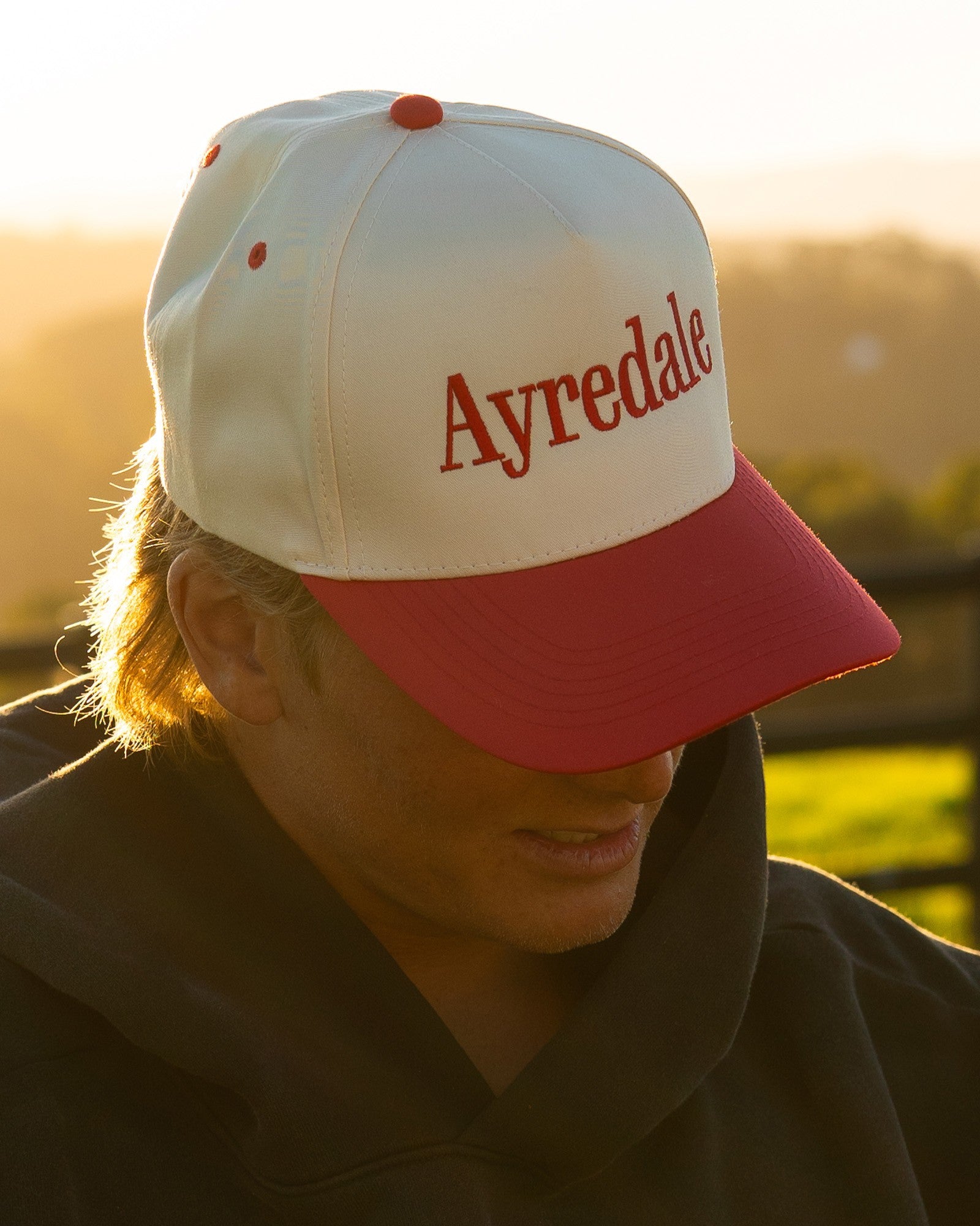 Ayredale Ranch & Co two-tone snapback cap with a cream crown, red brim, and embroidered red Ayredale wordmark.
