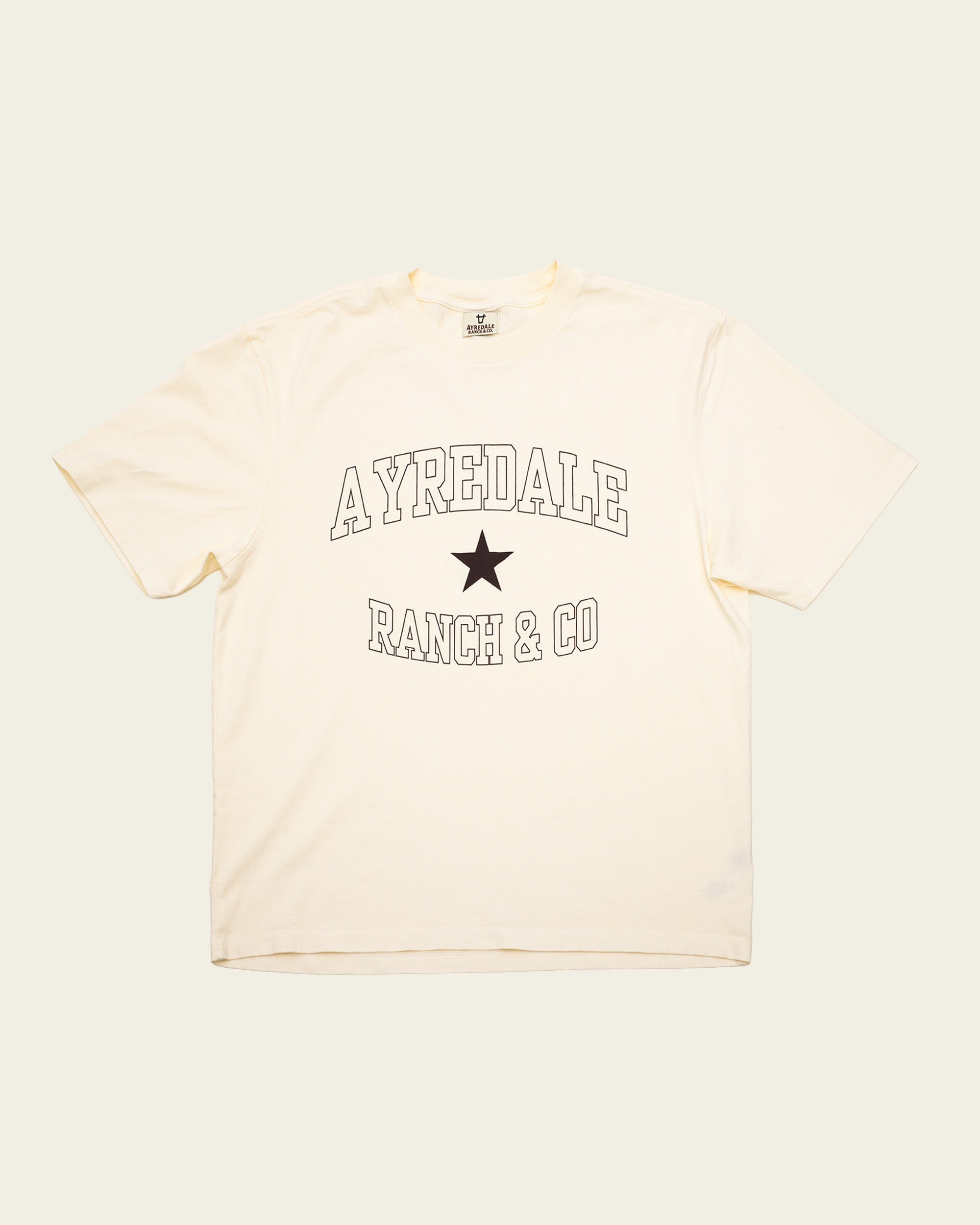 Ayredale Ranch & Co cream t-shirt with black collegiate-style text and a central star graphic on the chest.