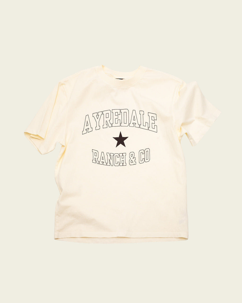 Ayredale Ranch & Co cream cotton t-shirt featuring a black collegiate-style logo and star graphic on the chest.
