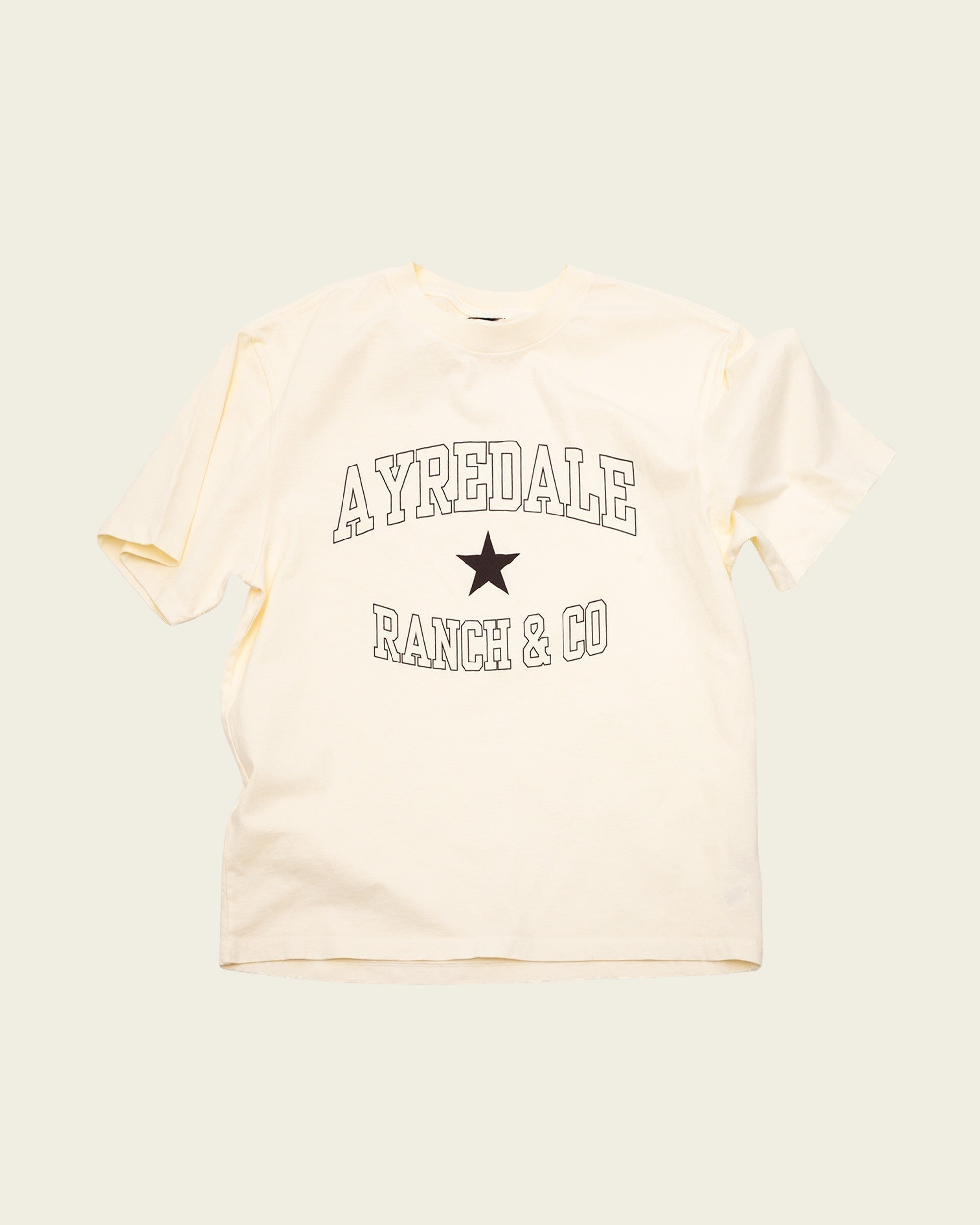 Ayredale Ranch & Co cream cotton t-shirt featuring a black collegiate-style logo and star graphic on the chest.