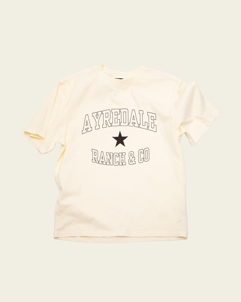 Ayredale Ranch & Co cream cotton t-shirt featuring a black collegiate-style logo and star graphic on the chest.