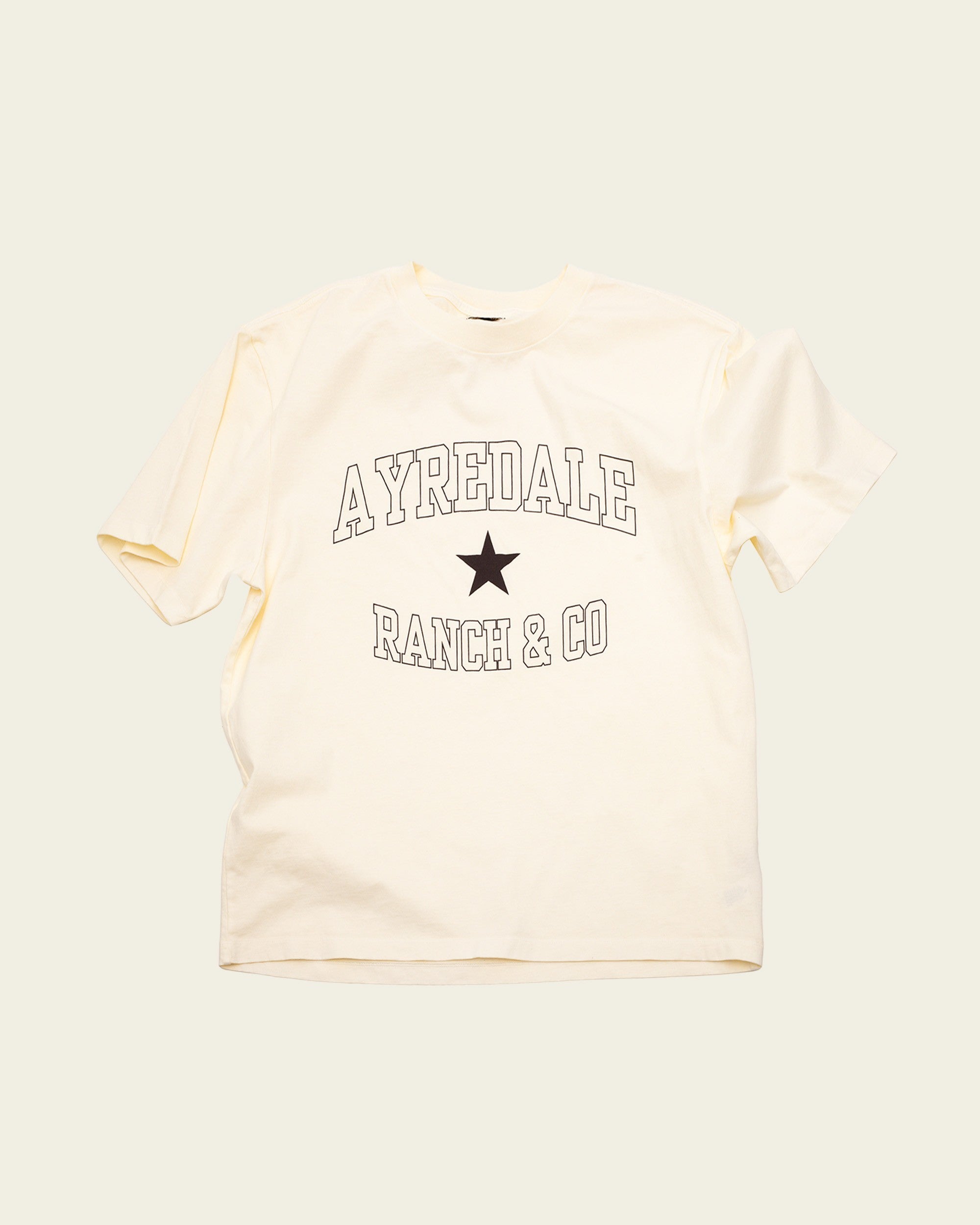 Ayredale Ranch & Co cream cotton t-shirt featuring a black collegiate-style logo and star graphic on the chest.