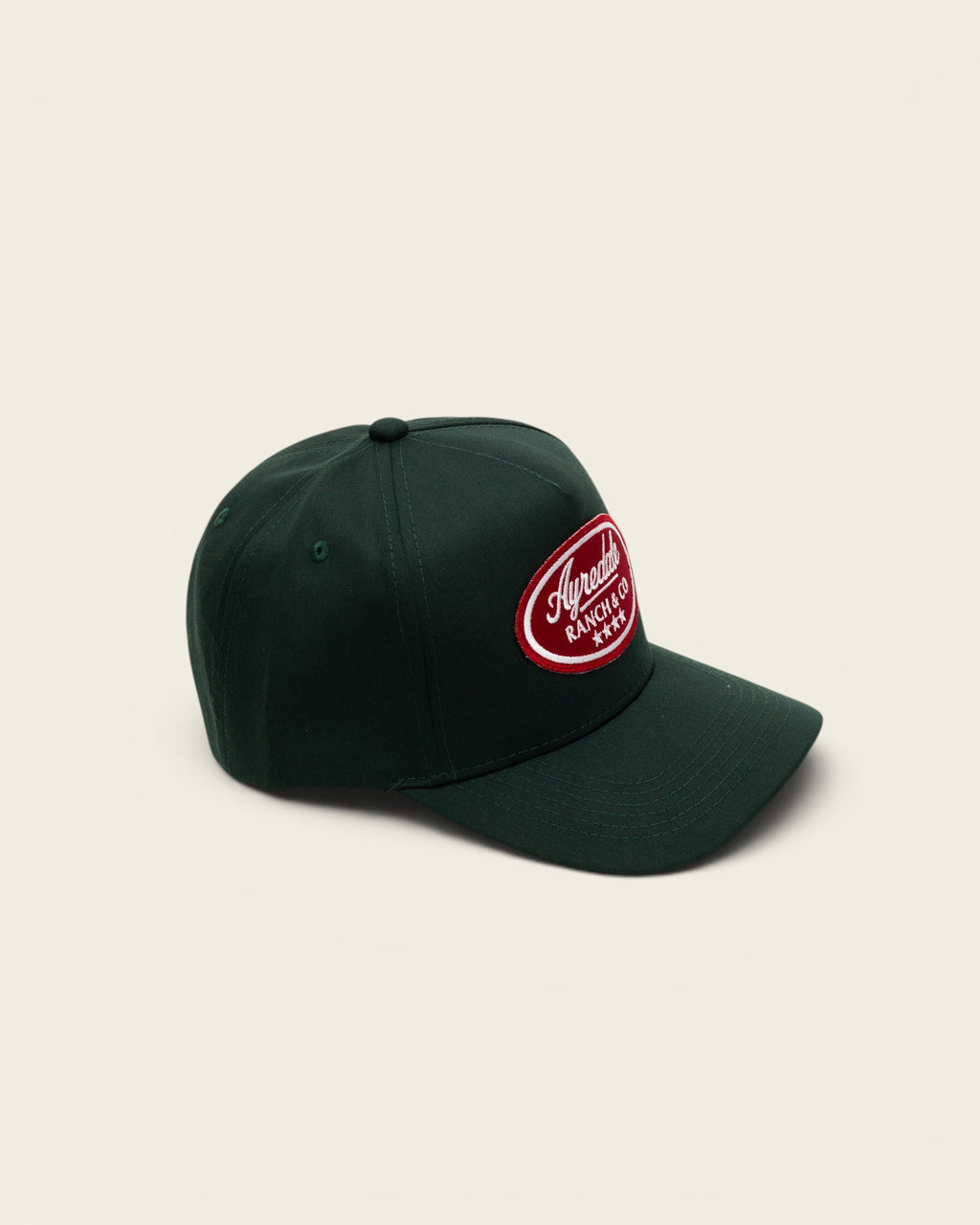Ayredale Ranch & Co dark green baseball cap with a red oval patch logo and four white stars on a white background