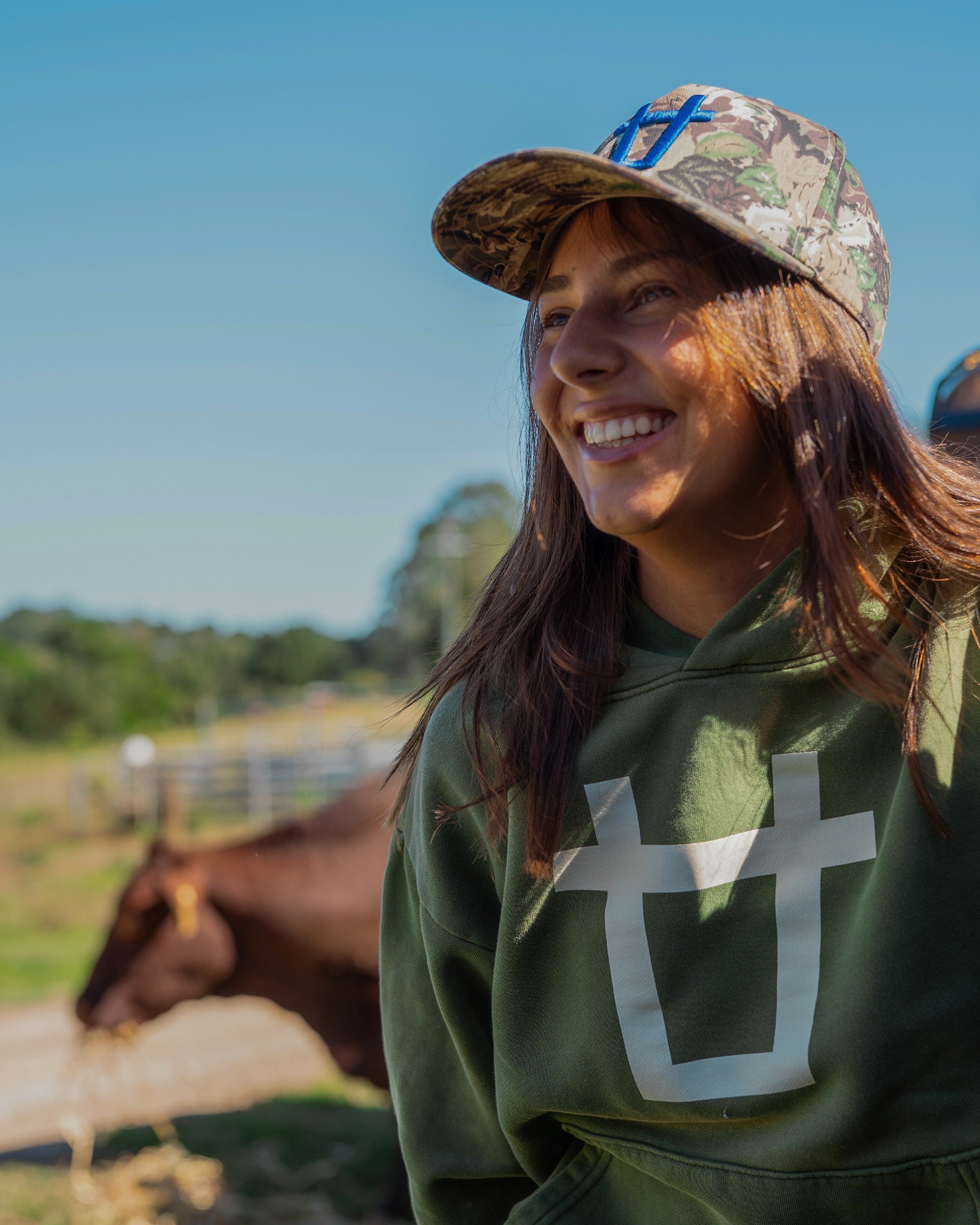 Ayredale Ranch & Co green heavyweight fleece hoodie with oversized white brand mark on chest. Model wears camouflage cap.