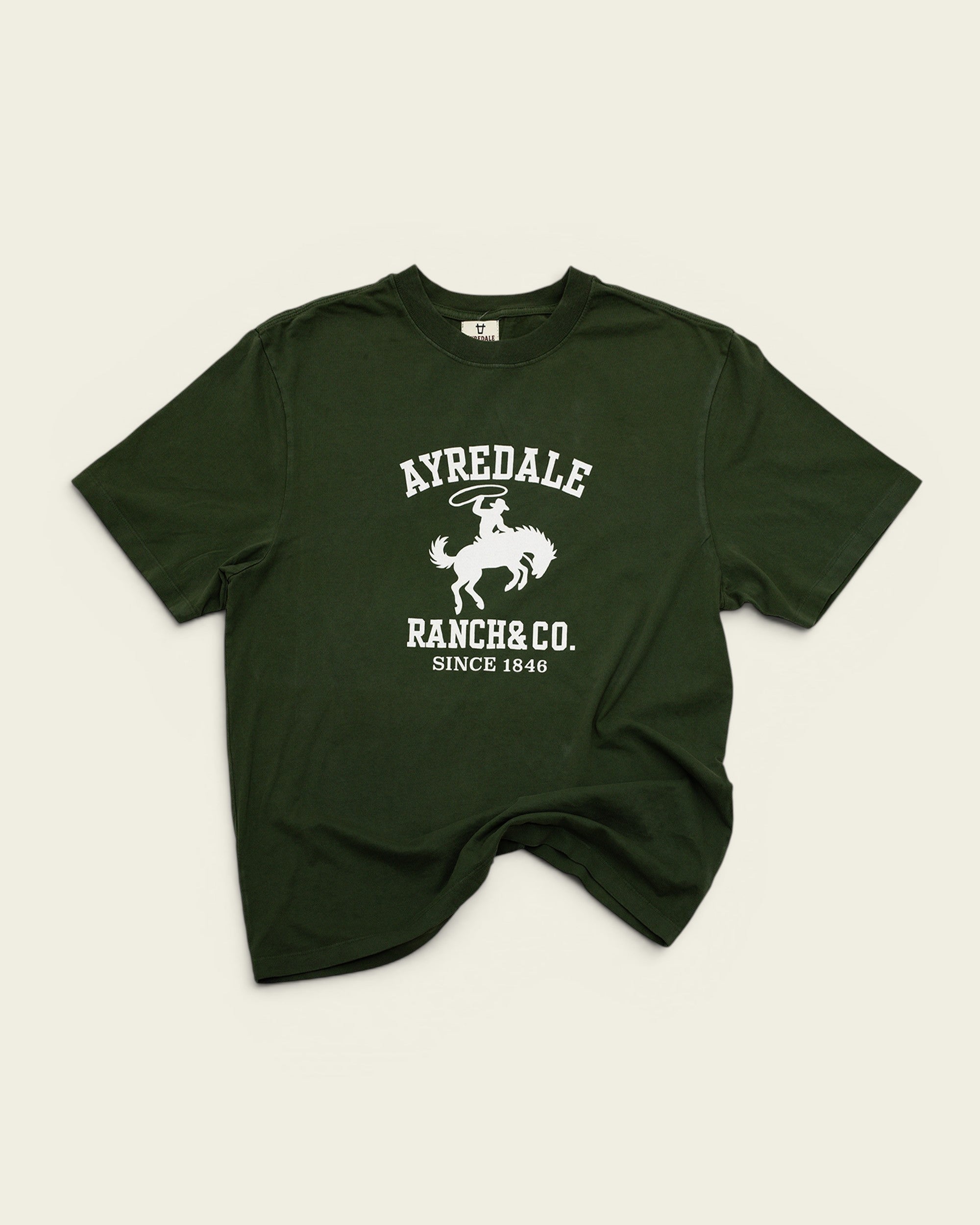 Ayredale Ranch & Co dark green cotton t-shirt featuring a white graphic of a cowboy on a bucking horse