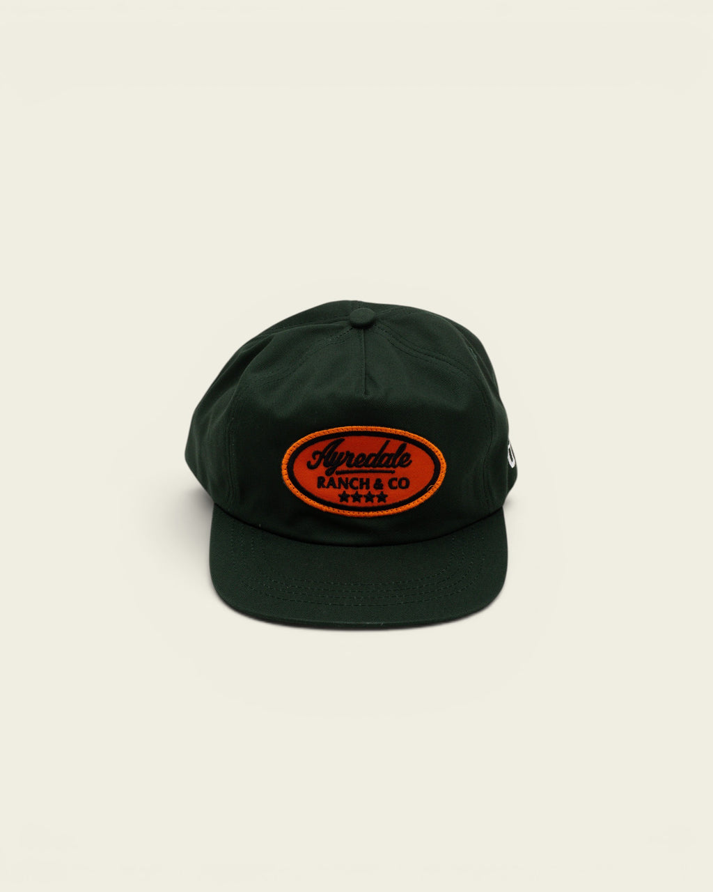 Ayredale Ranch & Co dark green baseball cap with an oval orange patch featuring black embroidered branding