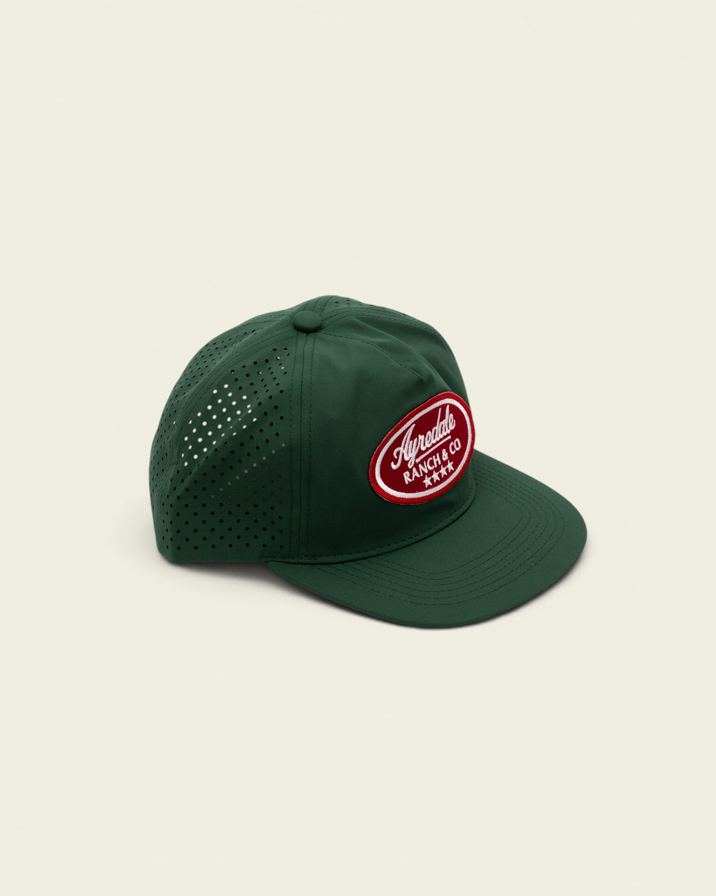 Ayredale Ranch & Co dark green performance baseball cap with laser-cut ventilation holes and red oval logo patch.