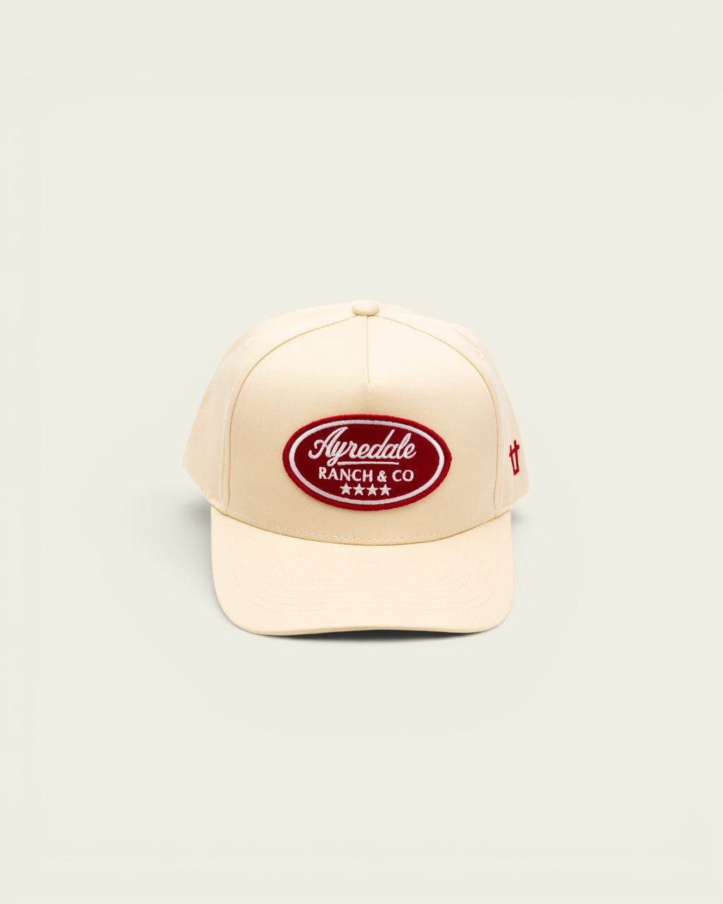 Off-white baseball cap by Ayredale Ranch & Co featuring a red oval patch with white embroidered text and four stars.