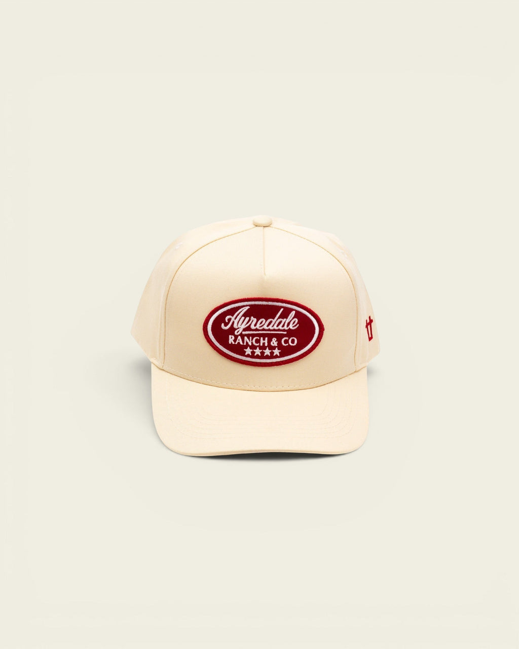 Off-white baseball cap by Ayredale Ranch & Co featuring a red oval patch with white embroidered text and four stars.
