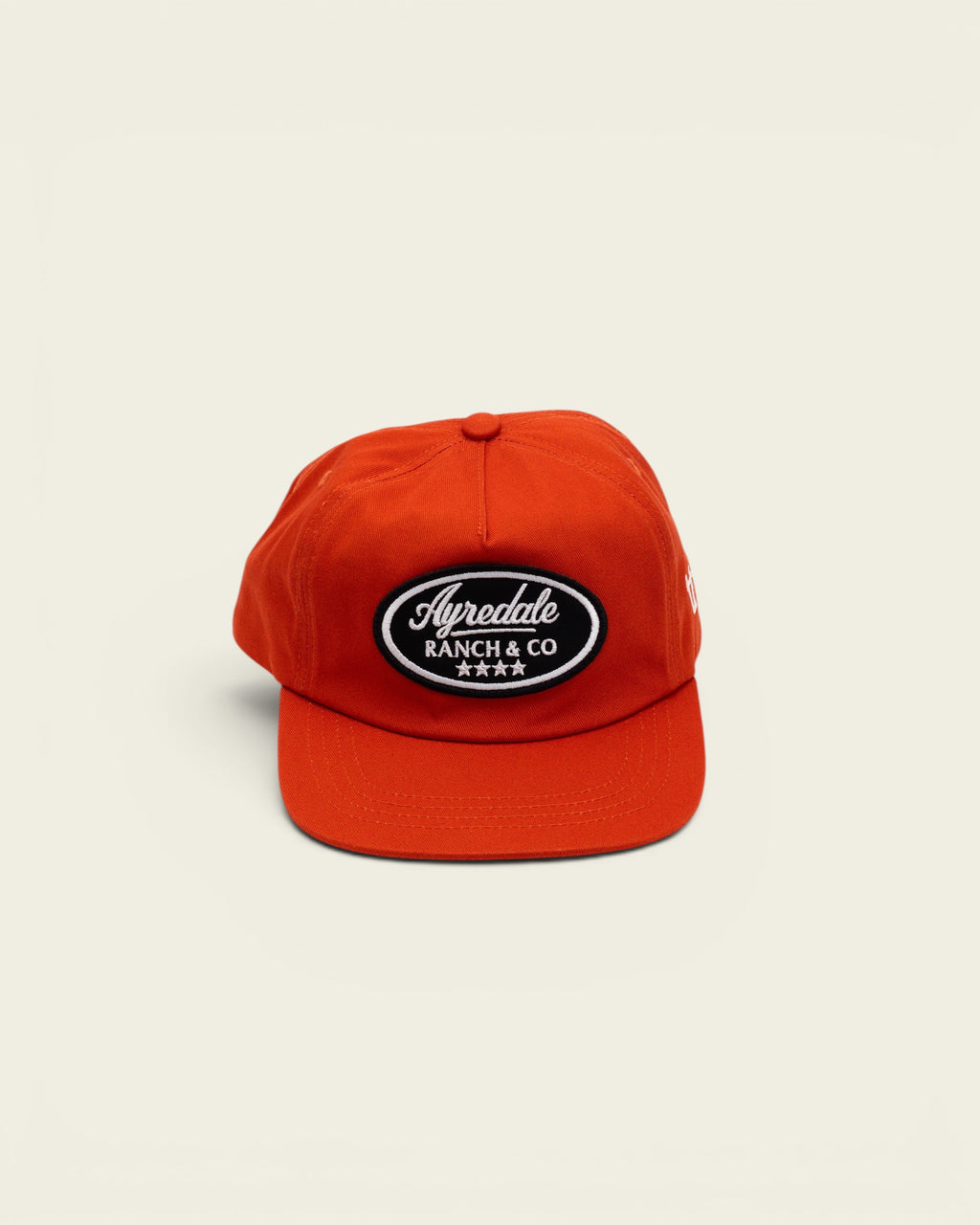 Ayredale Ranch & Co bright orange baseball cap with a black oval patch featuring white embroidered text and stars