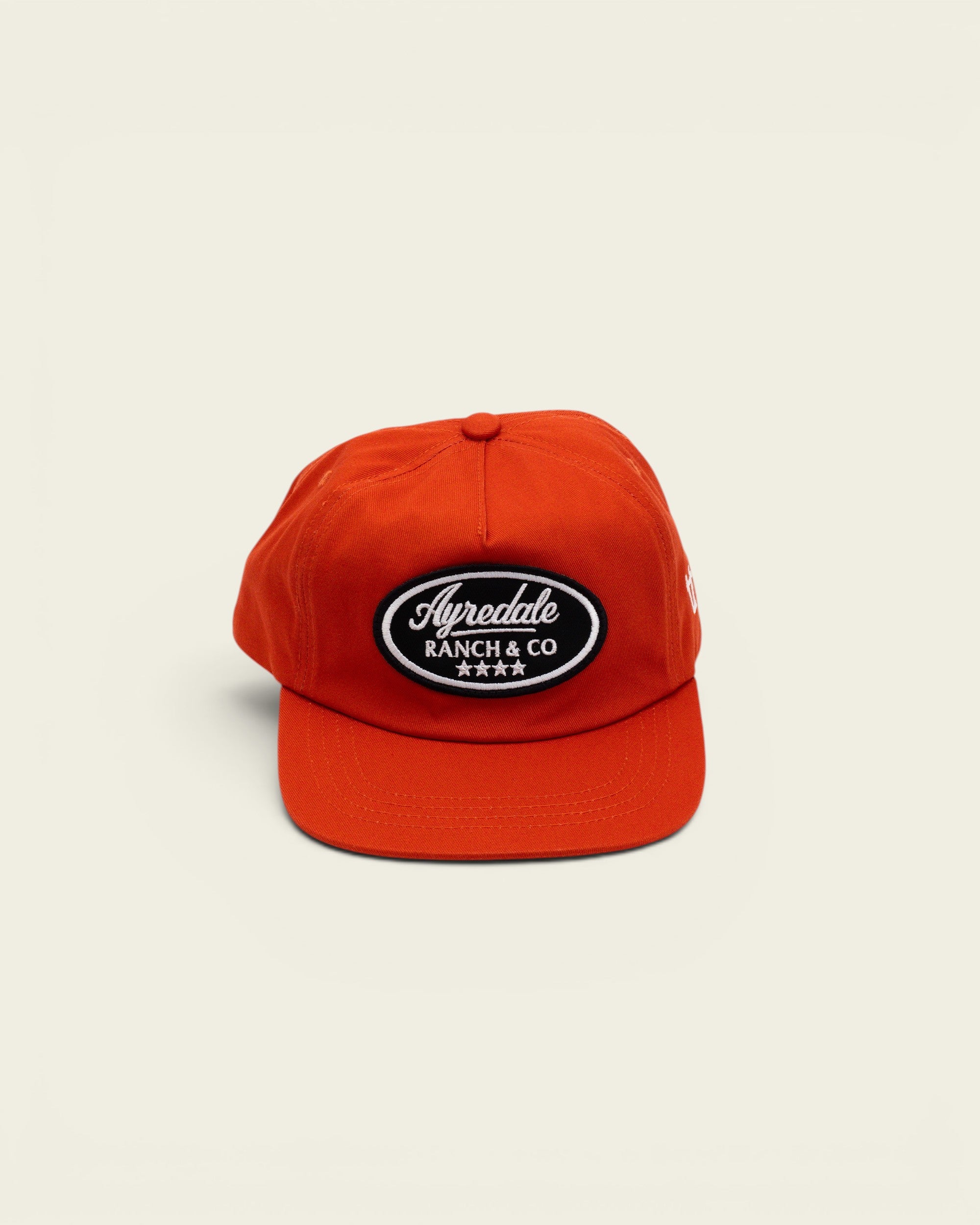 Ayredale Ranch & Co bright orange baseball cap with a black oval patch featuring white embroidered text and stars