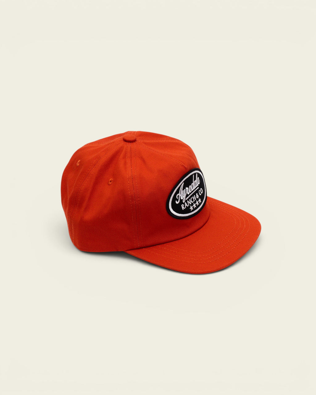 Ayredale Ranch & Co bright orange baseball cap with a black oval patch featuring white brand text and star details.
