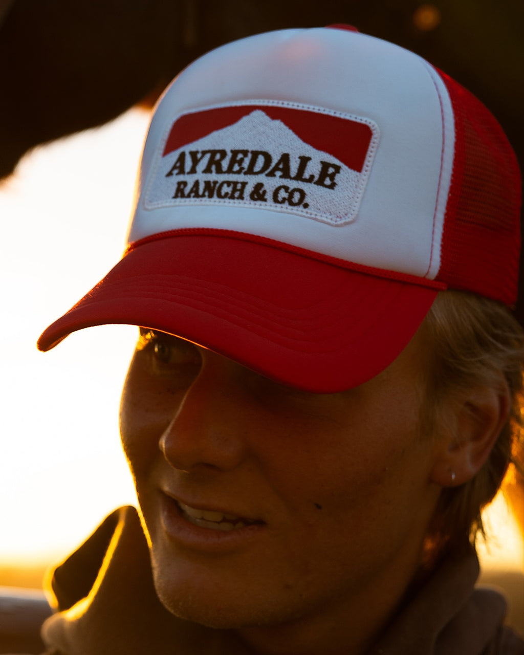 Ayredale Ranch & Co Mount Warning white and red trucker hat with embroidered patch and rope detail on a person